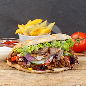 DÃÂ¶ner Kebab Doner Kebap fast food in flatbread with fries on a wooden board square photo