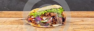 DÃÂ¶ner Kebab Doner Kebap fast food in flatbread on a wooden board panorama photo