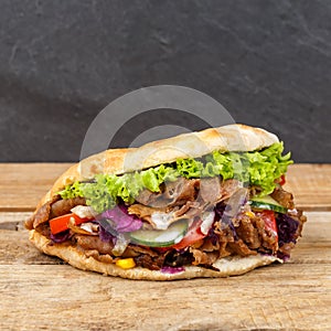 DÃÂ¶ner Kebab Doner Kebap fast food in flatbread on a wooden board square photo