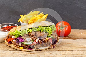 DÃÂ¶ner Kebab Doner Kebap fast food meal in flatbread with fries on a wooden board and copyspace copy space photo