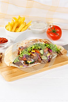 DÃÂ¶ner Kebab Doner Kebap slice fast food in flatbread with French Fries on a wooden board portrait format photo