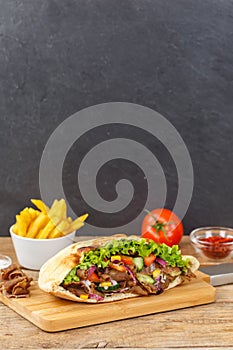 DÃÂ¶ner Kebab Doner Kebap slice fast food in flatbread with French Fries on a wooden board portrait format photo
