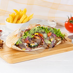 DÃÂ¶ner Kebab Doner Kebap slice fast food in flatbread with French Fries on a wooden board square photo