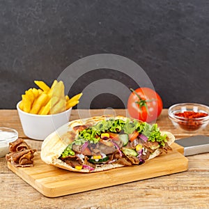 DÃÂ¶ner Kebab Doner Kebap slice fast food in flatbread with French Fries on a wooden board square photo