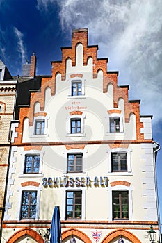 View on historic old building with gabled roof against blue sky, logo of local traditional SchlÃÂ¶sser Alt brewery