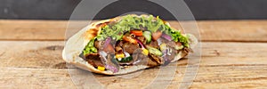 DÃ¶ner Kebab Doner Kebap fast food in flatbread on a wooden board panorama with copyspace copy space