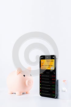 E banking concept. Mobile phone with internet online bank app. Pig bank with credit card on white background. Online