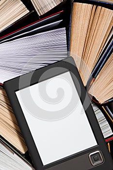 The e-book with a clean white screen rests on the open multi-colored books. ready to read