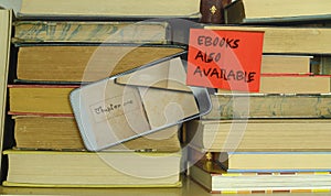 e book concept with stack of books,e book reader and sign with message e books also available