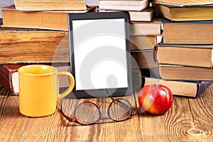 E-book, cup of coffee and glasses next to a stack of vintage books in the library. Space for text