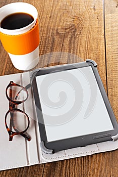 e-book, glasses and cup of coffee on a wooden table. Space for text