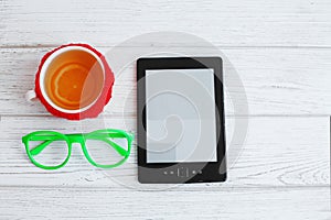 E-book, glasses and a cup of tea on a white background. Top view