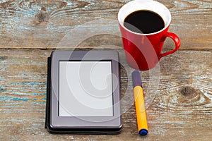 E-book reader and coffee cup on wooden table