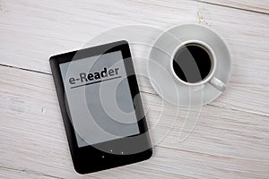 E-book reader and coffee cup on wooden table