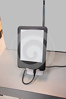 An e-book reader device in black matte on metal stand