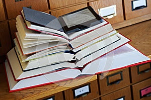 E-book Reader on top of Stack of Books in a Library