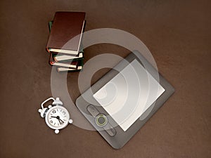 An e-book, stack of books and clock. Old and new way of reading. The concept of education training. preparing for exams