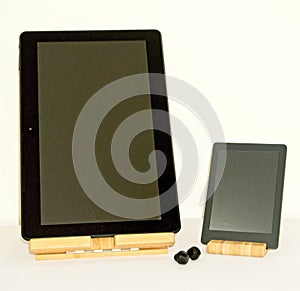 E-book and a tablet on a wooden lift stand together with some wireless headphones