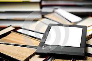 The e-book with a white screen lies on the open multi-colored books that lie on a dark background, close-up