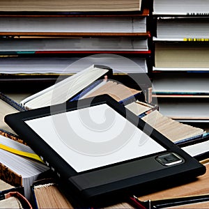 The e-book with a white screen lies on the open multi-colored books that lie on a dark background, close-up