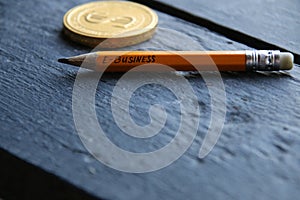 E-Business concept, gold coin and pencil with the inscription