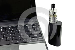 An e-cigarette sitting next to a laptop