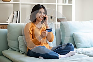 E-commerce Concept. Happy Arab Woman Holding Credit Card And Talking On Cellphone