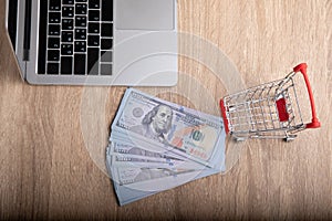 E-commerce concept for top-view photo of laptop, fake US dollar banknote and trolley