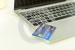 E-Commerce and Online shopping Concept. Close up of mockup fake credit card on notebook computer laptop on white desk
