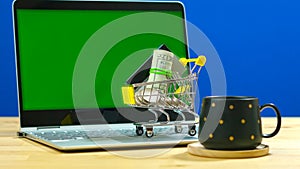 E-commerce retail shopping concept with miniature shopping cart and laptop.