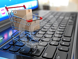 E-commerce. Shopping cart with cardboard boxes on laptop.