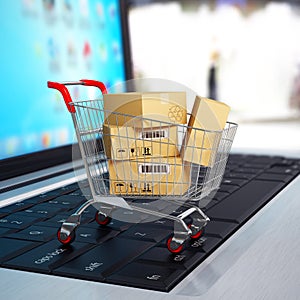E-commerce. Shopping cart with cardboard boxes on laptop.