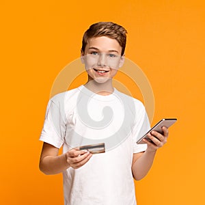 Cute teenager using mobile application and credit card
