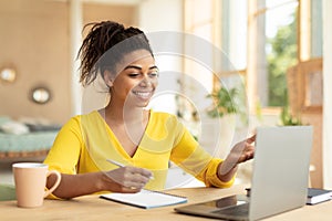 E-learning concept. Happy black female teacher having video chat with students, talking at laptop webcamera