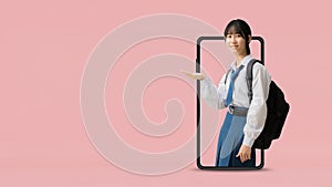 E learning idea concept, Asian student girl wearing uniform hold backpack with hand holding open palm up coming out big smart phon