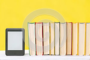 E-learning and knowledge. E-book reader and a stack of books on a yellow background. Copy space. Mock up. Concept of education and