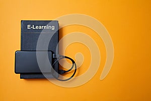 E-library. E-learning, online education or e-book. Webinar, internet courses. Book and hard drive on yellow background