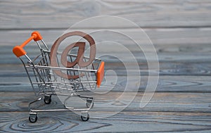 An e-mail symbol, shopping cart on a wood board background.