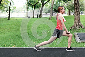 Side view of healthy Asian woman stretching her legs before run in park. Fitness and exercise concept.