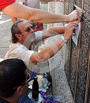 At the EAA Memorial Wall a Man Rubs a Deceased Loved Ones Name on Paper