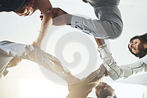 We each complete our circle of strength. Closeup shot of a group of businesspeople linking their arms in solidarity.