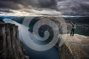 Eagle head viewpoint near Kjeragbolten Lysebotn Norway Young Woman in Victory pose