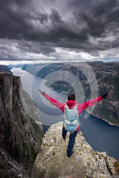 Eagle head viewpoint near Kjeragbolten Lysebotn Norway Young Woman in Victory pose