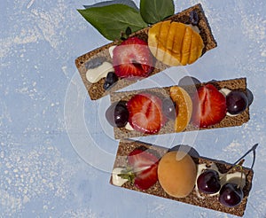 Ealthy and tasty toasts with curd cheese, fruits and berries on a blue background