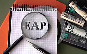 EAP - acronym under magnifying glass on the background of calculator and banknotes
