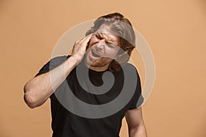 The Ear ache. The sad man with headache or pain on a pastel studio background.