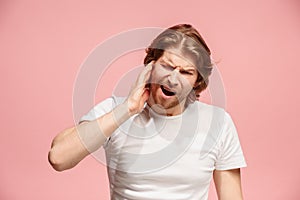 The Ear ache. The sad man with headache or pain on a pink studio background.