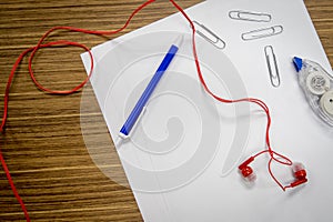 Ear buds and office supplies on a desk.