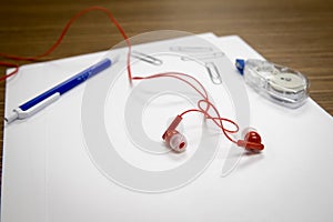 Ear buds and office supplies on a desk.