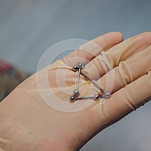 ear jewelry, piercing in hand with a disposable glove.